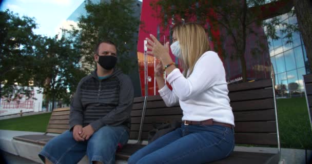Couple sitting on bench wearing mask talking — Stock Video