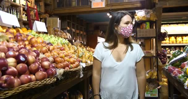 Vrouw in masker op zoek naar groenten en fruit — Stockvideo