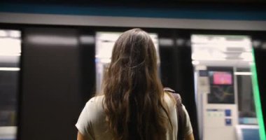 Maskeli kadın metroda tren bekliyor.