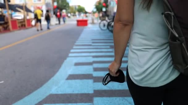 Mujer sosteniendo máscara en la mano caminando — Vídeo de stock