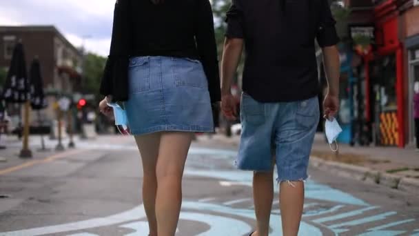 Hombre y mujer sosteniendo máscara en la mano caminando — Vídeos de Stock