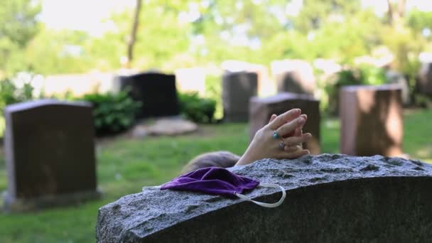 Mezar taşının yanında maskeli bir kadın dua ediyor. — Stok video
