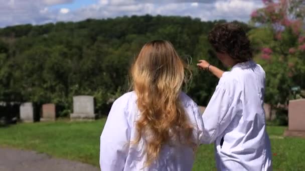 Woman talking showing something in cemetery — Stock Video