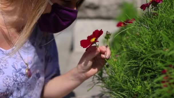 Maskeli kadın taze çiçekler kokluyor. — Stok video