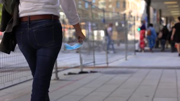 Kobieta ręka gospodarstwa maska chodzenie po chodniku — Wideo stockowe