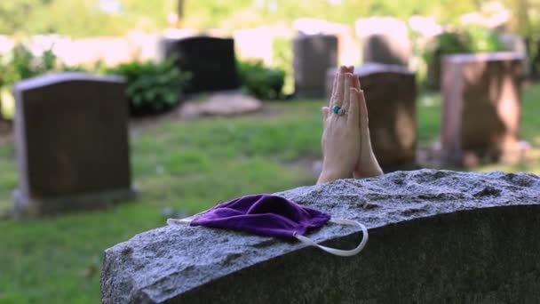 Жінка, що приєднується до руки біля надгробного каменю з маскою — стокове відео