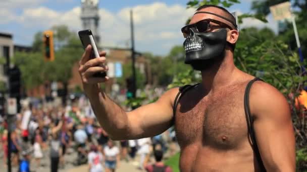 Man med mask tar video av rally i telefon — Stockvideo