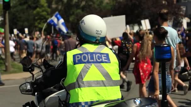 Policja siedzi na rowerze patrząc na protest — Wideo stockowe