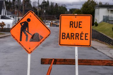Turuncu yol kapalı tabelalar ve inşaat barikatları yol çalışması ve tamiratı gösteriyor, Rue Barree Fransızca yazılmış.