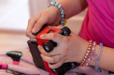 Child assembling a red toy car using colorful building blocks, developing fine motor skills and creativity during playtime