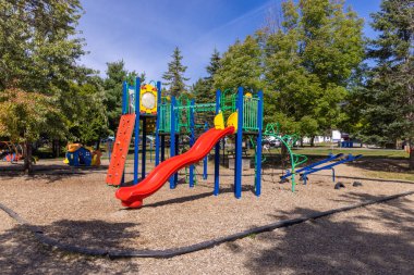 Modern oyun alanı ekipmanları açık hava eğlencesi ve fiziksel aktiviteyi destekleyen güneşli bir günde oynayan çocuklar için hazır.