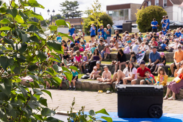 Семьи и дети собираются в городском парке, наслаждаясь развлечениями на свежем воздухе в солнечный день