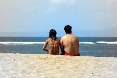 İki aşık sahilde oturuyor. İnsanlar ile deniz manzarası.