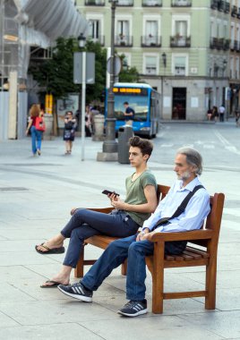 2017.05.31, Madrid, Ispanya. Madrid sokaktaki insanlar. Sokaktaki bankta oturan yaşlı bir adam ve genç bir çocuk. Beni adın olarak ara..