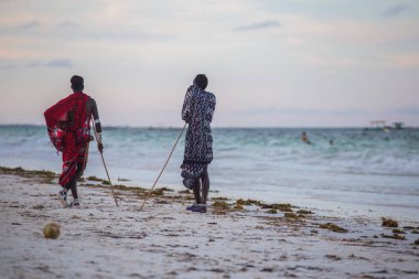 2018.02.21, Kiwengwa, Tanzanya. Tanzanya seyahat. Okyanus arka plan üzerinde duran iki etnik adam. İnsanlar sahilde.