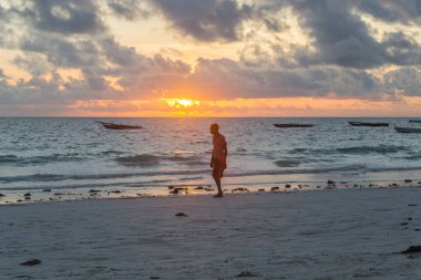 2018.02.21, Kiwengwa, Tanzanya. Tanzanya seyahat. Günbatımı okyanus arka plan üzerinde ayakta yalnız etnik adam. İnsanlar sahilde.