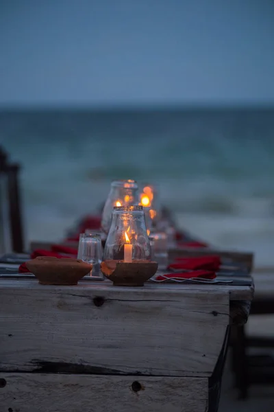 Candles on the table on background of ocean. Table and chairs on the bech tonight.