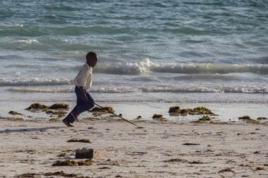 2018.02.21, Kiwengwa, Tanzanya. Tanzanya seyahat. Kıyı boyunca çalışan çocuk. Sahilde insanlar. Tanzanya okullu çocuk.