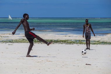 2018.02.21, Kiwengwa, Tanzanya. Tanzanya seyahat. Arka plan mavi gökyüzü ve okyanus plaj futbol oynamak çekici bir Afrika erkek.