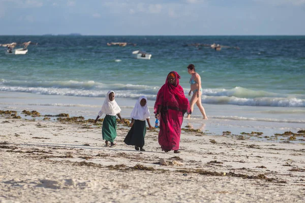 2018.02.21, Kiwengwa, Tanzanya. Bir grup genç insan sahilde yürüyüş. Öğrenciler eve gidiyor. Çocuklar eve gidiyor.
