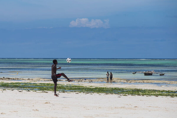 2018.02.21, Kiwengwa, Tanzania. Travel around Tanzania. An attractive African men playing football on the beach on background of blue sky and ocean.