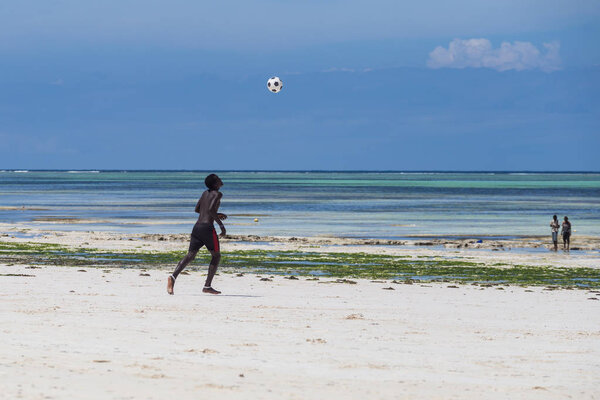 2018.02.21, Kiwengwa, Tanzania. Travel around Tanzania. An attractive African men playing football on the beach on background of blue sky and ocean.