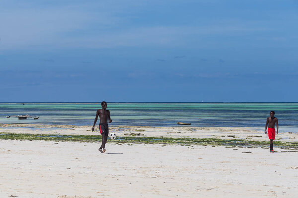 2018.02.21, Kiwengwa, Tanzania. Travel around Tanzania. An attractive African men playing football on the beach on background of blue sky and ocean.