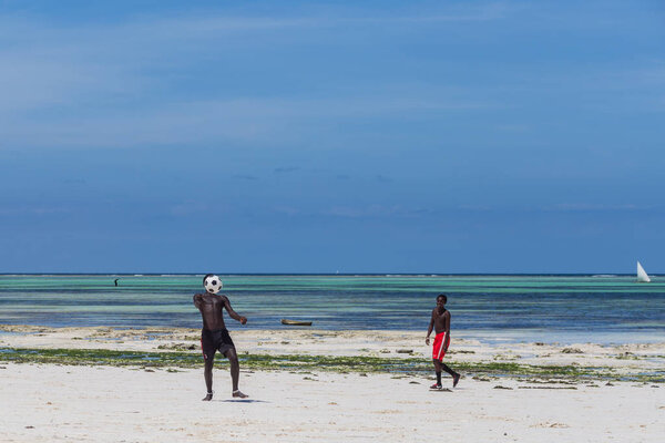 2018.02.21, Kiwengwa, Tanzania. Travel around Tanzania. An attractive African men playing football on the beach on background of blue sky and ocean.
