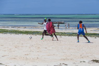 2018.02.21, Kiwengwa, Tanzanya. Tanzanya seyahat. Bir grup çekici bir Afrika adam arka plan mavi gökyüzü ve okyanus plaj futbol oynamak. Zanzibar eğlence.
