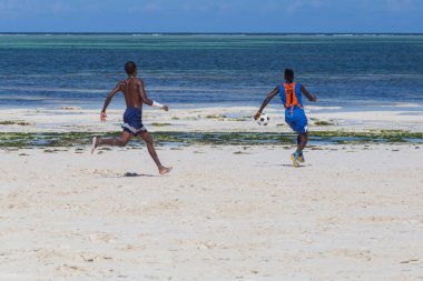 2018.02.21, Kiwengwa, Tanzanya. Tanzanya seyahat. Bir grup çekici bir Afrika adam arka plan mavi gökyüzü ve okyanus plaj futbol oynamak. Zanzibar eğlence.