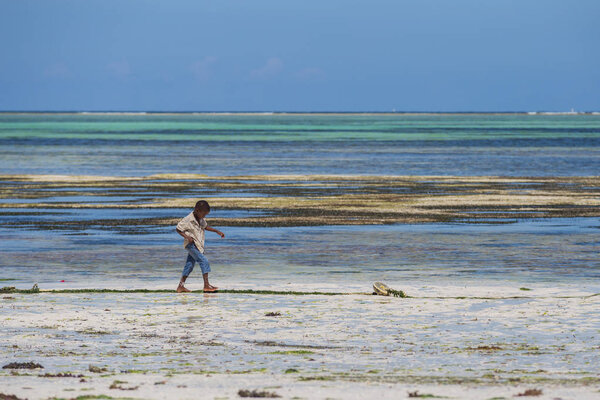 2018.02.21, Kiwengwa, Tanzania. Travel around Tanzania. A little boy on the coast on background of blue sky and ocean.