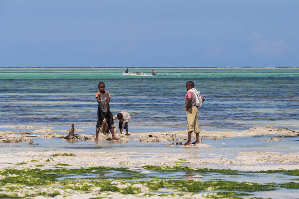 2018.02.21, Kiwengwa, Tanzania. Travel around Tanzania. A group of African fishermen standing on the beach on background of blue sky and ocean.