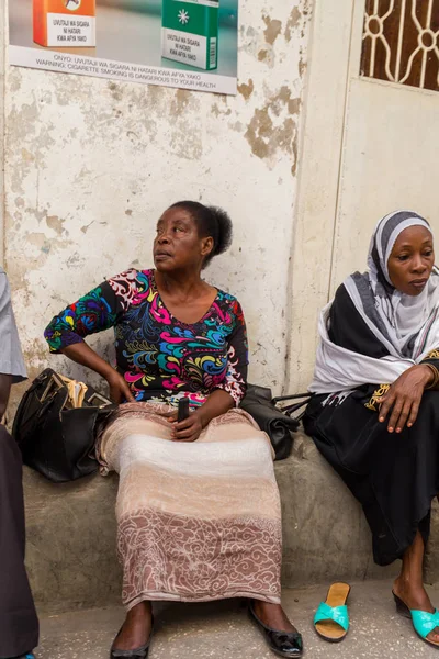 2018.02.24, Stone Town, Zanzibar, Tanzanya. Afrika çevresinde seyahat. Grup Afrika halkının duvar tarafından sokakta oturan.