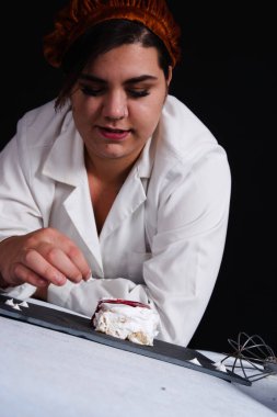 Öğrenci siyah arka planda pasta hazırlıyor.