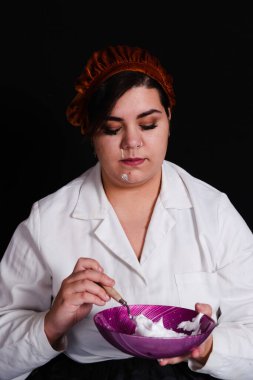 Öğrenci siyah arka planda pasta hazırlıyor.