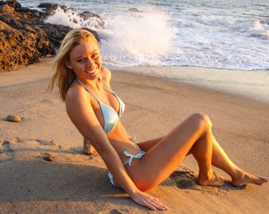 Malibu California batımında sahilde mavi bikinili güzel kadın.