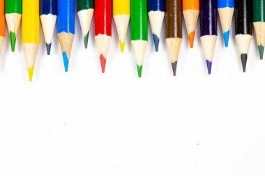 Beyaz bir arka plan karşı üst üste dizilmiş renkli kalemler.