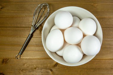 Yumurta bir yemeğin kullanıldıklarını Şef için bekleyen bir çırpma teli yanında derin beyaz bir kase içinde bir grup