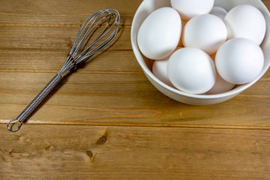 Yumurta bir yemeğin kullanıldıklarını Şef için bekleyen bir çırpma teli yanında derin beyaz bir kase içinde bir grup