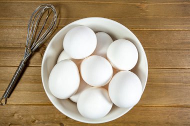 Yumurta bir yemeğin kullanıldıklarını Şef için bekleyen bir çırpma teli yanında derin beyaz bir kase içinde bir grup