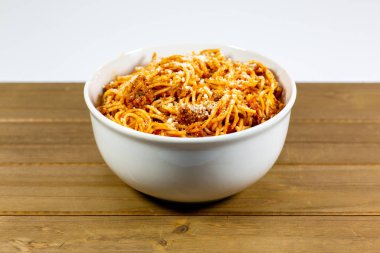 Spagetti Bolognese yenmek için bekleyen ahşap mutfak masasında derin beyaz bir kase