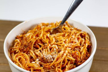Spagetti Bolognese yenmek için bekleyen ahşap mutfak masasında derin beyaz bir kase