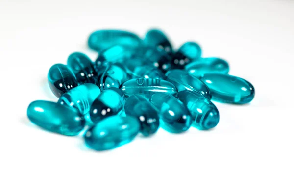 Two clear blue pills against the while surface of a pharmacy table.