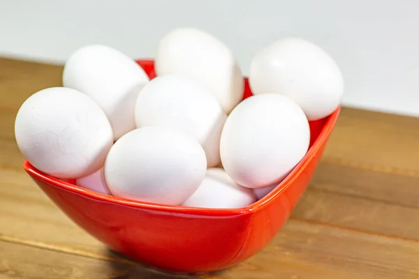 A group of eggs inside a deep red bowl waiting for the chef to use them in a meal