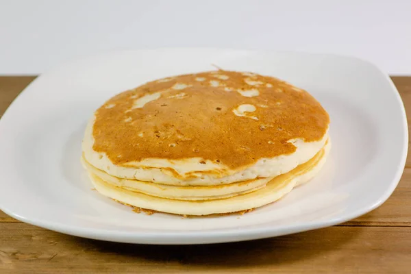 Μια Στοίβα Από Pancakes Χρυσή Ένα Λευκό Πιάτο Που Κάθονται — Φωτογραφία Αρχείου
