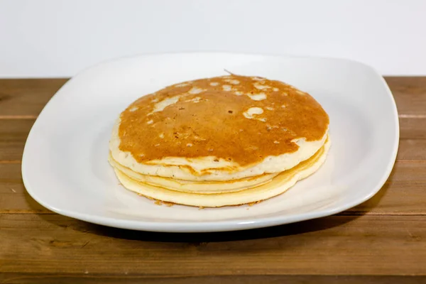 Μια Στοίβα Από Pancakes Χρυσή Ένα Λευκό Πιάτο Που Κάθονται — Φωτογραφία Αρχείου