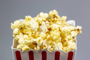 Patlamış mısır üstünde beyaz bir sayaç ile taşan bir kırmızı soyulmuş patlamış mısır küçük kova