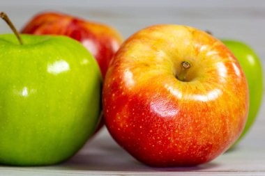 Mutfak masasının üstünde yenmek için bekleyen yeşil ve kırmızı elma