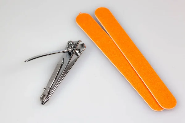 Nail clipper and two nail files sitting on a white counter