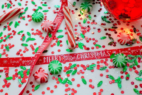 Decoration with red fluid filled Christmas ornament ball and two green filled ornament balls surrounded by a red Have Yourself A Merry Christmas ribbon, a set of Christmas lights and peppermint candy